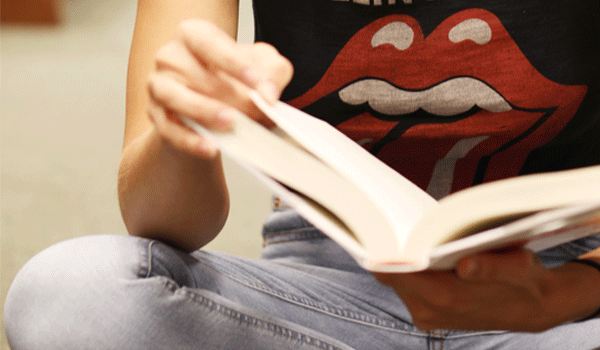 young woman sitting crossed-legged and reading a book